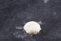 Pon un poco de harina en una esquina de la encimera. Da la vuelta a tu trozo de masa boleada y ponla sobre la harina