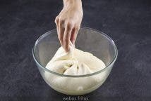 Pasado este tiempo, y sin sacar la bola del cuenco, coge un pellizco del borde y llévalo al centro. Sella un poco